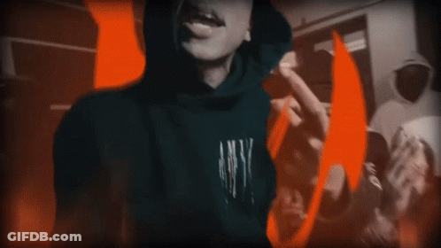A Person In A Hoodie Is Standing In Front Of A Fire GIF