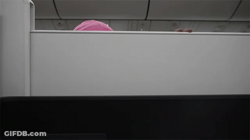 A Person In A Pink Hat Is Peeking Out From Behind A White Wall GIF