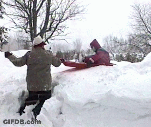 A Person In A Pink Hooded Jacket Is Sledding Down A Snow Covered Hill GIF