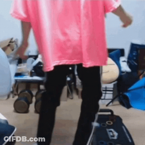 A Person In A Pink Shirt And Black Pants Is Dancing In A Room . GIF