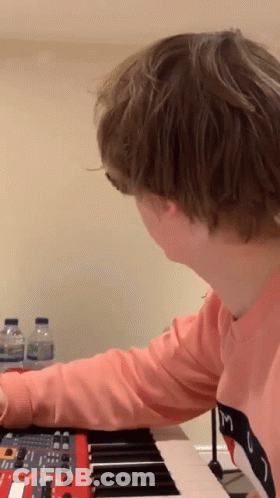 A Person In A Pink Shirt With The Letter M On It Is Playing A Keyboard GIF