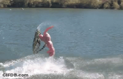 A Person In A Pink Suit Is Riding A Wave On A Surfboard GIF