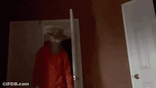 A Person In A Red Hoodie Is Standing In A Dark Room . GIF