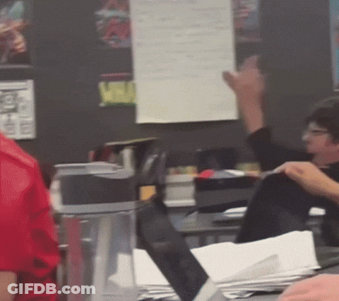 A Person In A Red Shirt Is Raising Their Hand In A Classroom GIF
