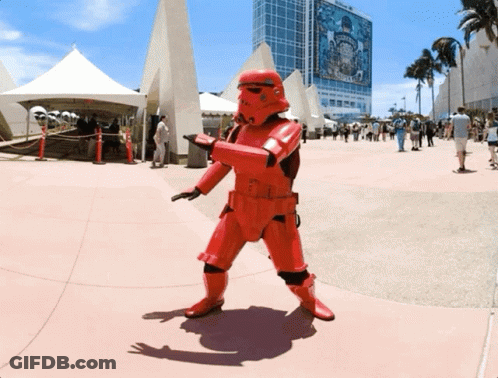 A Person In A Red Storm Trooper Costume Stands In Front Of A Building That Says Disney GIF