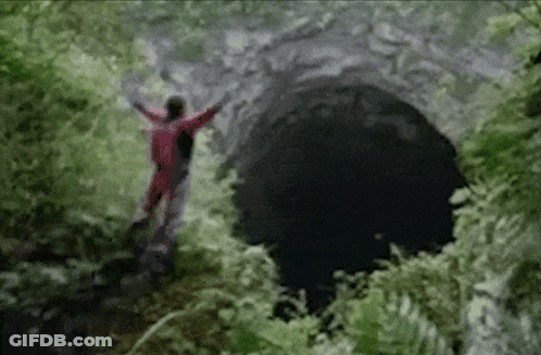 A Person In A Red Suit Is Standing In A Cave GIF