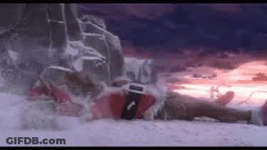 A Person In A Santa Suit Is Laying On A Snowy Hill . GIF