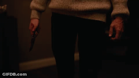 A Person In A Sweater Holding A Knife In Their Hand GIF