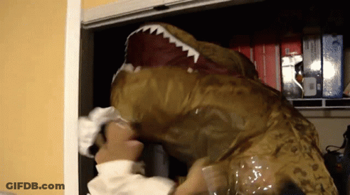 A Person In A T-Rex Costume Reaches Into A Closet Full Of Boxes GIF