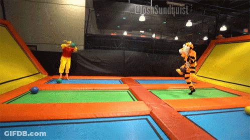 A Person In A Tigger Costume Is Jumping On A Trampoline With Another Person In A Clown Costume GIF