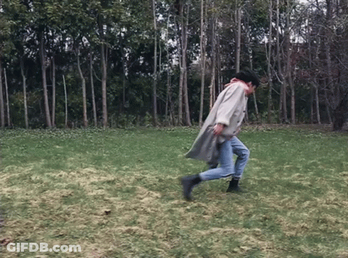A Person In A Trench Coat Is Running In A Field GIF
