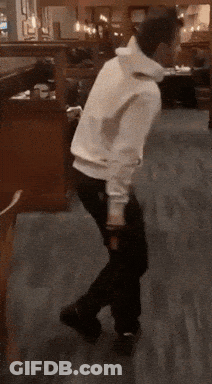 A Person In A White Hoodie Is Dancing In A Restaurant GIF