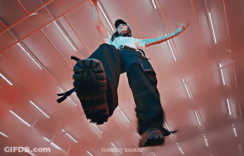 A Person In A White Shirt And Black Pants Is Standing In A Room With A Red Ceiling GIF