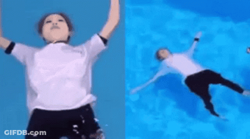 A Person In A White Shirt Is Jumping Into A Pool Of Water . GIF