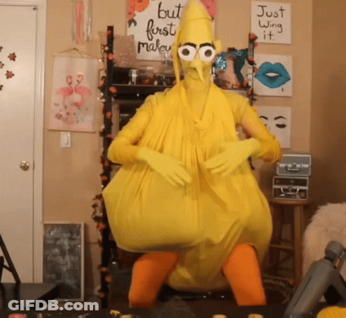 A Person In A Yellow Chicken Costume With A Sign That Says But First Make It GIF