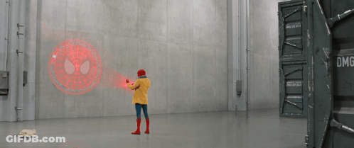 A Person In A Yellow Jacket Is Standing In A Room With A Spider Man Logo On The Wall GIF