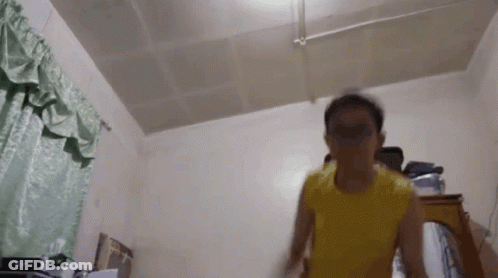 A Person In A Yellow Shirt Is Standing In A Room GIF