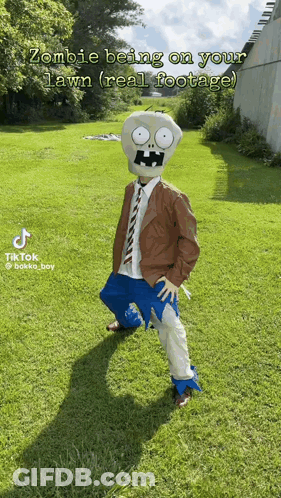 A Person In A Zombie Costume Is Standing On A Lush Green Lawn GIF