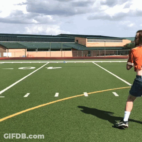 A Person In An Orange Shirt Is Running On A Football Field With The Letter O In The Background GIF