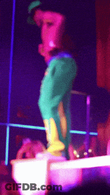 A Person In Green Pants And Yellow Boots Is Standing On A Stage GIF