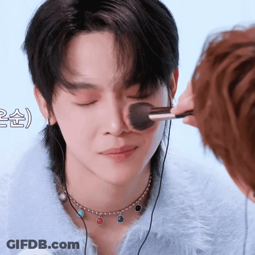 A Person Is Applying Makeup To Another Person 'S Face With A Brush GIF