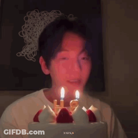 A Person Is Blowing Out Candles On A Birthday Cake . GIF