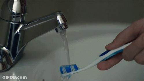 A Person Is Brushing Their Teeth In A Sink With Water Running From The Faucet GIF