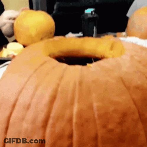 A Person Is Carving A Large Pumpkin With A Hole In It GIF
