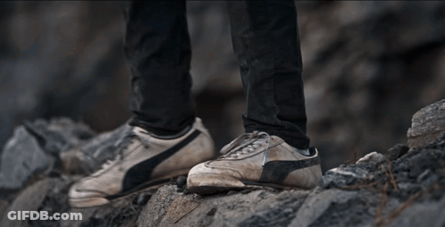 A Person Is Climbing Up A Rocky Hillside GIF