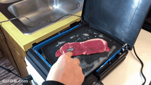A Person Is Cooking A Steak On A Griddle In A Kitchen GIF