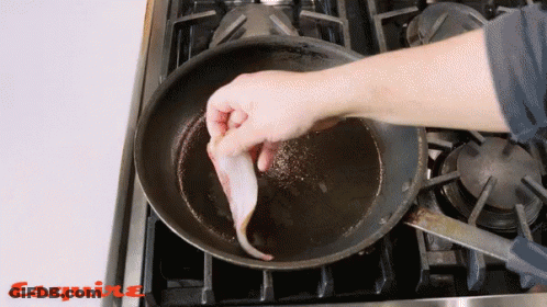 A Person Is Cooking Bacon In A Frying Pan With Esquire Written On The Stove Top GIF