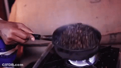 A Person Is Cooking Food In A Frying Pan On A Stove Top . GIF