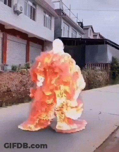A Person Is Covered In Flames While Walking Down The Street GIF
