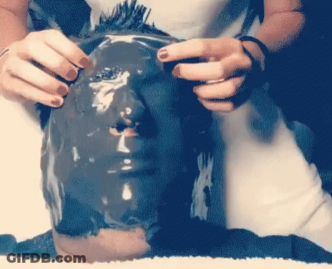A Person Is Covering Their Face With A Black Mask GIF