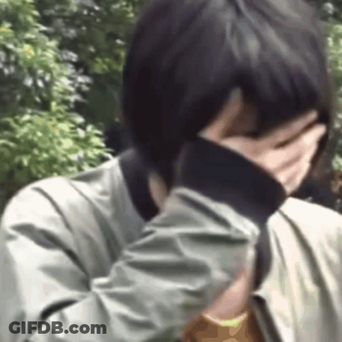 A Person Is Covering Their Face With Their Hand . GIF