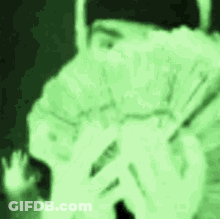 A Person Is Covering Their Face With Their Hands In A Green Light . GIF