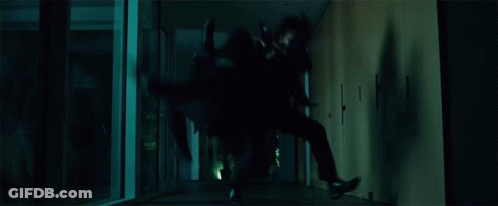 A Person Is Crawling Through A Dark Hallway In A Dark Room . GIF