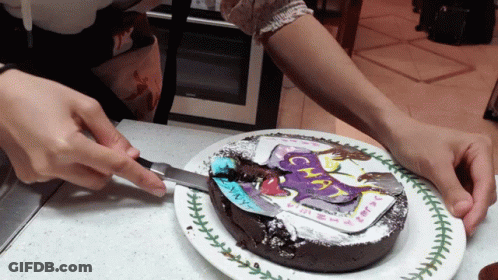 A Person Is Cutting A Chocolate Cake With A Picture Of A Unicorn On It GIF