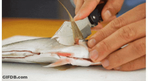 A Person Is Cutting A Fish With A Knife On A Table GIF
