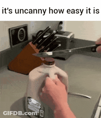 A Person Is Cutting A Gallon Of Milk With A Knife In A Kitchen . GIF