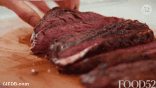 A Person Is Cutting A Large Piece Of Meat On A Cutting Board GIF
