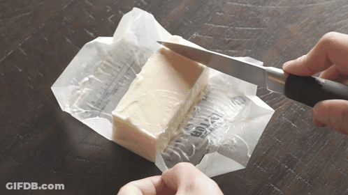 A Person Is Cutting A Piece Of Butter With A Knife On A Table GIF