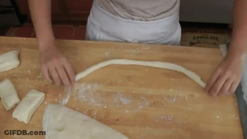 A Person Is Cutting A Piece Of Dough On A Wooden Table With An Apple Pie Box In The Background GIF