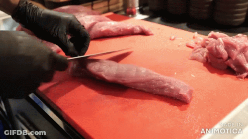A Person Is Cutting A Piece Of Meat On A Red Cutting Board That Says Made In Animotica GIF
