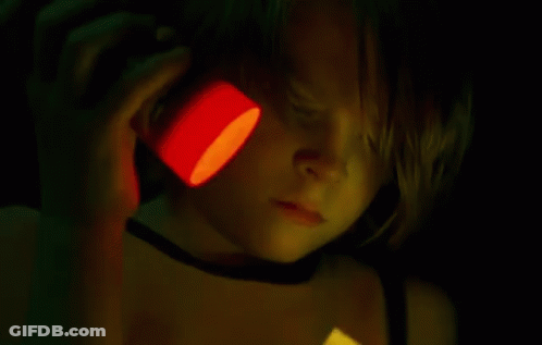 A Person Is Cutting A Piece Of Paper With Scissors In A Dark Room GIF