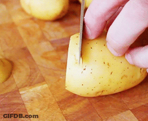 A Person Is Cutting A Potato With A Knife On A Cutting Board GIF