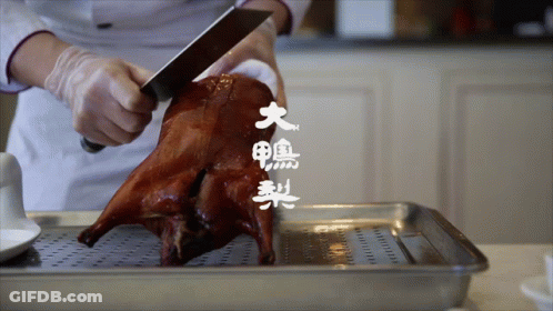 A Person Is Cutting A Roasted Duck With Chinese Writing On The Bottom GIF