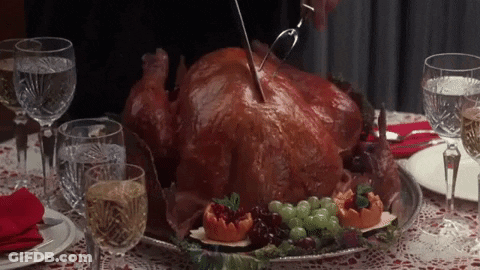 A Person Is Cutting A Turkey On A Table With Glasses Of Wine GIF