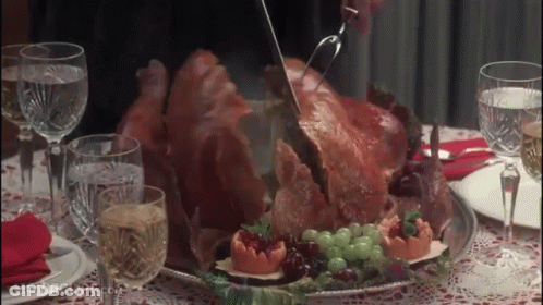 A Person Is Cutting A Turkey On A Table With Wine Glasses And Water GIF