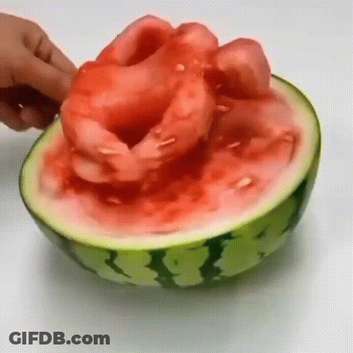 A Person Is Cutting A Watermelon Into Pieces On A Table . GIF